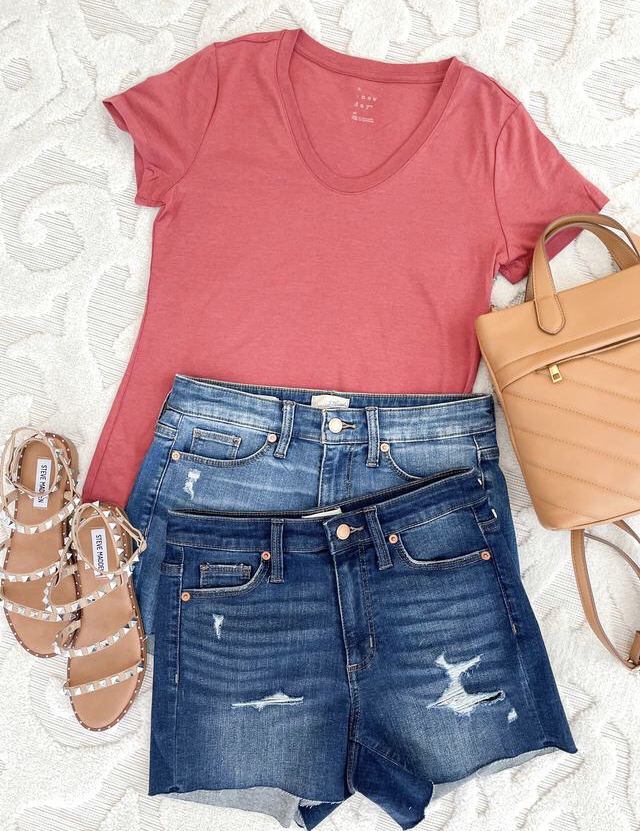Clothing Flatlay with $5 Red T-shirt, dark wash and medium wash jean shorts, and strappy sandals with a tan cross body purse